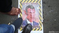 Tampak poster wajah Emmanuel Macron banyak diinjak para massa aksi.  