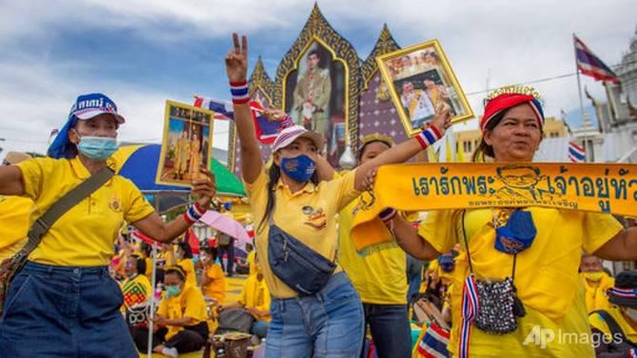 Pendukung monarki menampilkan gambar Raja Maha Vajiralongkorn, Ratu Suthida dan mendiang Raja Bhumibol Adulyadej saat mereka berkumpul di depan Grand Place di Bangkok, Thailand, Minggu, 1 November 2020. (Foto AP / Wason Wanichakorn)