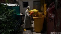 Petugas kebersihan memakai APD lengkap membuang sampah medis ke tempat yang telah disiapkan dengan baik dan benar.