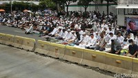 Tampak massa menunaikan salat di tengah jalan di dekat Bawaslu.