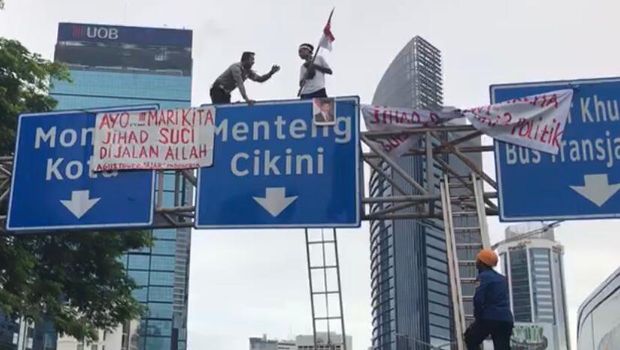 Wadirlantas Polda Metro AKBP Hari Purnomo membujuk pemasang spanduk di tiang rambu.