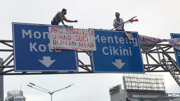 Wadirlantas Polda Metro AKBP Hari Purnomo membujuk pemasang spanduk di tiang rambu.