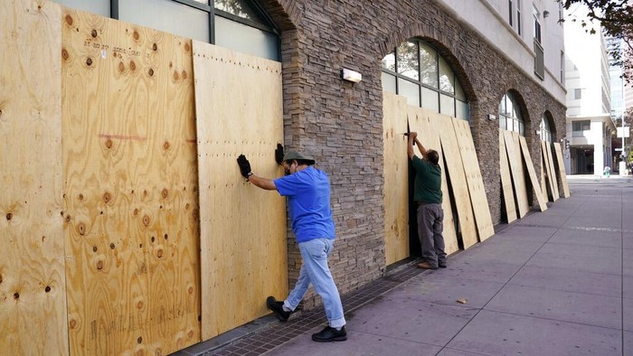 A pedestrian passes a boarded up entrance at the Saks Fifth Avenue store, Friday, Oct. 30, 2020, in Beverly Hills, Calif. Retailers, including Nordstrom, Tiffany and Saks Fifth Avenue, are boarding up their windows and planning to add extra security personnel in some of their locations ahead of the contentious presidential election on Tuesday. (AP Photo/Chris Pizzello)
