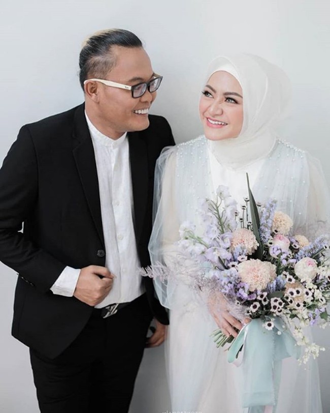 Nathalie Holscher dan Sule berpose seperti pasangan yang sedang di mabuk cinta di pemotretan jelang pernikahan. Sule tampil dengan setelan jas hitam dan kemeja putih, sedangkan Nathalie memakai dress putih dengan detail tulle dan mutiara yang menyebar di bagian dada busananya. Foto: Instagram dan YouTube Ferdinan Sule