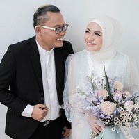 Nathalie Holscher dan Sule berpose seperti pasangan yang sedang di mabuk cinta di pemotretan jelang pernikahan. Sule tampil dengan setelan jas hitam dan kemeja putih, sedangkan Nathalie memakai dress putih dengan detail tulle dan mutiara yang menyebar di bagian dada busananya. Foto: Instagram dan YouTube Ferdinan Sule