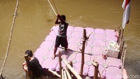 Seorang anak bernama Muhammad Sauzah Putra Rohman bersiap menyeberangkan warga di Sungai Ciliwung.