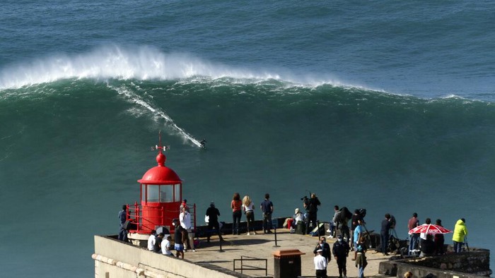 Uji Adrenalin! Berselancar di Gelombang Besar Badai Epsilon A surfer rides a wave during a tow surfing session at Praia do Norte or North Beach in Nazare, Portugal, Thursday, Oct. 29, 2020. A big swell generated earlier in the week by Hurricane Epsilon in the North Atlantic, reached the Portuguese west coast drawing big wave surfers to Nazare. (AP Photo/Pedro Rocha)