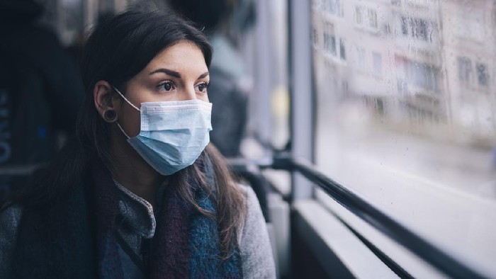 1209025695 Young woman wearing protective face mask, she sitting in bus transportation in the city.