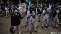Buruh membawa atribut aksi seperti poster dan bendera.
