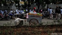 Tampak seorang pedagang berjualan es cendol di antara massa yang tengah melakukan aksi unjuk rasa.