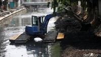 Lumpur yang mengendap dipindahkan ke tepi sungai.