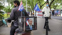 Seorang kurir pengiriman mengendarai sepeda motor berhiaskan potret Presiden AS Donald Trump dan bendera Trump 2020 di Beijing. AP Photo/Mark Schiefelbein  