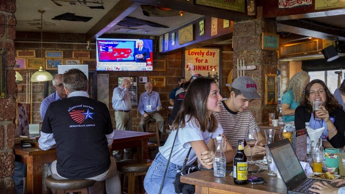 A group of U.S. Democrats supporters gather at a roadhouse restaurant to view U.S. media coverage of the U.S. presidential election in Bangkok, Thailand, Wednesday, Nov. 4, 2020. (AP Photo/Gemunu Amarasinghe)