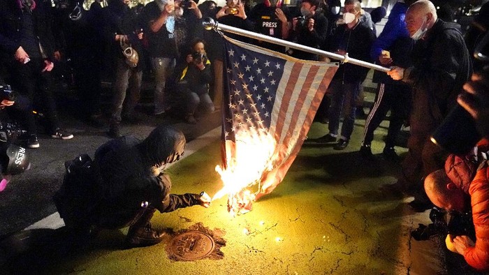 A protester lights an American flag on fire during a demonstration Wednesday, Nov. 4, 2020, in Portland, Ore. (AP Photo/Marcio Jose Sanchez)