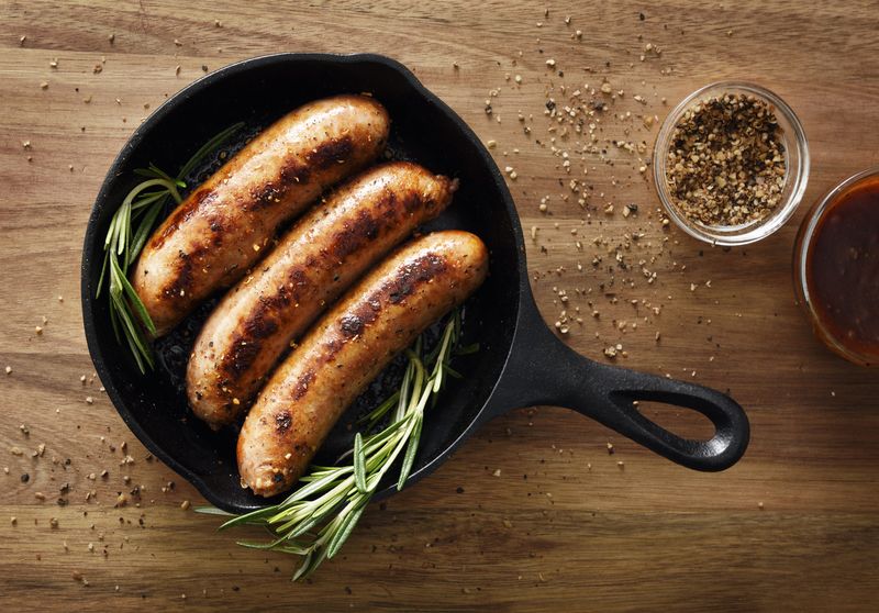 Three sausages in a cast iron skillet with seasoning