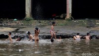 Anak-anak terlihat sangat semringah saat bermain di bantaran Sungai Ciliwung tersebut.