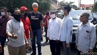 Ganjar dan Gibran kemudian berjalan menuju salah satu kios sparepart mobil. Ganjar bertanya ke penjual tentang penjualannya di tengah pandemi.