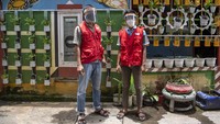Dua pria berompi merah nampak sibuk berkeliling kampung di jalan Kapten Abdulah, Lorong Mari RT 02 RW 01, Kelurahan Talang Bubuk, Kecamatan Plaju, Palembang, Sumatera Selatan.   