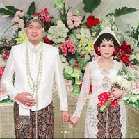 Tata Janeeta menikah dengan mengenakan kebaya putih dan kain batik. Busana pengantin tradisionalnya tersebut dirancang oleh desainer Anji Asmara. Penampilannya dipercantik dengan sanggul yang berhiaskan mahkota dan sematan bunga mawar merah, lengkap dengan paes.  Foto: Instagram