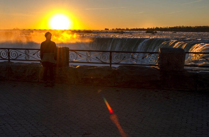A man watches the sun rise over Niagara Falls in Niagara Falls, Ontario, Canada on Wednesday, Nov. 4, 2020.  (Frank Gunn/The Canadian Press via AP)