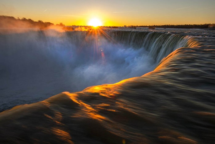 A man watches the sun rise over Niagara Falls in Niagara Falls, Ontario, Canada on Wednesday, Nov. 4, 2020.  (Frank Gunn/The Canadian Press via AP)