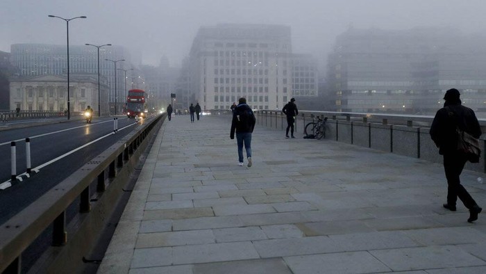 People walk over a foggy London Bridge towards the City of London financial district, on the first day of Britains second lockdown designed to save its health care system from being overwhelmed by people with coronavirus, in London, Thursday, Nov. 5, 2020. Britain joined large swathes of Europe in a coronavirus lockdown designed to save its health care system from being overwhelmed. Pubs, along with restaurants, hairdressers and shops selling non-essential items closed on Thursday until at least Dec. 2. (AP Photo/Matt Dunham)