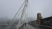 Orang-orang berjalan dalam kabut di Jembatan Westminster, London, Inggris.