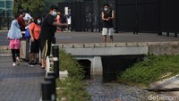 Sejumlah warga memberi makan ikan di saluran air yang berada di kawasan GBK. 