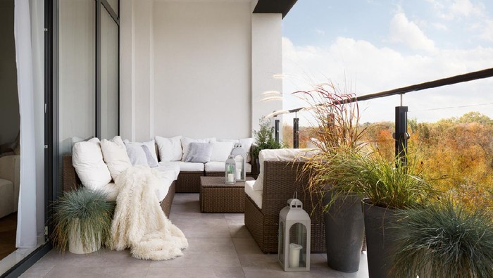Elegant decorated balcony with rattan outdoor furniture, bright pillows and plants