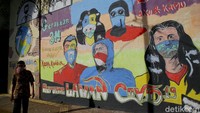 Warga melintas didepan mural COVID-19 dikawasan Jakarta Selatan, Senin (9/11/2020).   