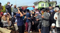 Seorang perempuan berkerudung hitam diduga masih kerabat almarhum Gatot terlihat tidak sadarkan diri, lalu dibawa ke luar area pemakaman.