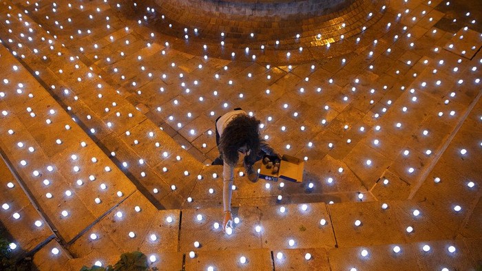 An activist turns on LED candles at a memorial for Israel's victims of COVID-19, in Jerusalem, Sunday, Nov. 8, 2020. (AP Photo/Oded Balilty)