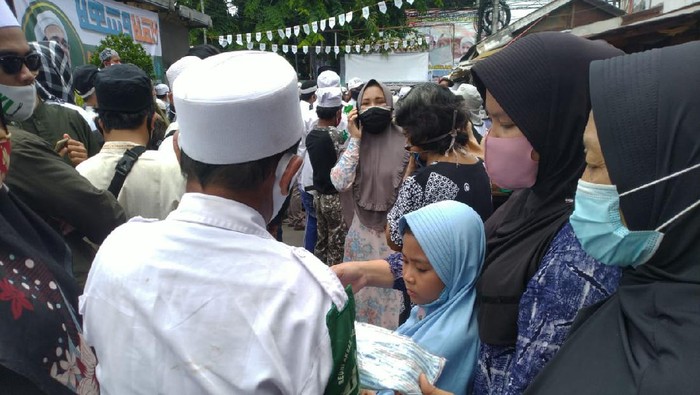 Laskar Pembela Islam (LPI) membagi-bagikan masker ke warga yang menunggu Habib Rizieq tiba di Petamburan