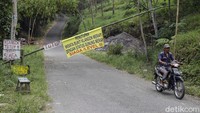 Seorang warga melintasi palang pintu wisata alam Bukit Klangon di Desa Glagaharjo, Cangkringan, Sleman, Yogyakarta.