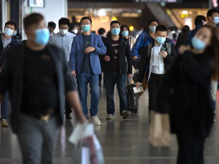 Travelers wearing face masks to protect against the coronavirus walk along a concourse at the Shanghai Hongqiao International Airport in Shanghai, Friday, Nov. 6, 2020. With the COVID-19 outbreak largely under control within its borders, air travel in China has mostly returned to pre-pandemic levels. (AP Photo/Mark Schiefelbein)