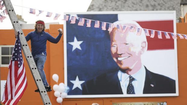 A man puts a US flag up in the town of Ballina, the ancestral home of President elect Joe Biden, in North West of Ireland, Saturday, Nov. 7, 2020. Biden was elected Saturday as the 46th president of the United States, defeating President Donald Trump in an election that played out against the backdrop of a pandemic, its economic fallout and a national reckoning on racism.  (AP Photo/Peter Morrison)