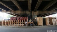 Seorang pedagang menunggu pembeli dengan duduk di depan jejeran furnitur di kolong flyover Kranji.