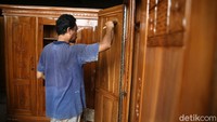 Pekerja melakukan proses finising pembuatan lemari kayu.