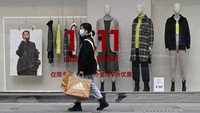 Seorang wanita yang mengenakan masker wajah untuk melindungi dari virus korona yang membawa barang belanjaannya di depan sebuah outlet yang menawarkan harga diskon Hari Jomblo di pusat perbelanjaan di Beijing. AP / Andy Wong