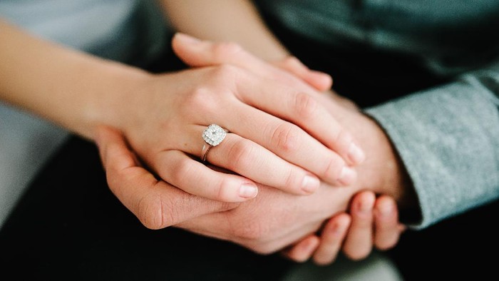 Close up of an elegant engagement diamond ring on woman finger. love and wedding concept.