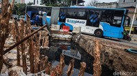 Bus Transjakarta melintas perlahan di dekat proyek bak penampungan air (kolakan) di Jalan Latumenten, Grogol Jakarta Barat, Kamis (12/11/2020).