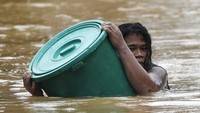 Seorang warga beraktivitas di tengah banjir yang terjadi akibat Topan Vamco yang menerjang kawasan Filipina. AP Photo/Aaron Favila.