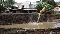 Lumpur dikeruk menggunakan ekskavator.