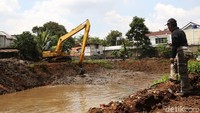 Seorang warga asyik memancing saat lumpur sungai sedang dikeruk.