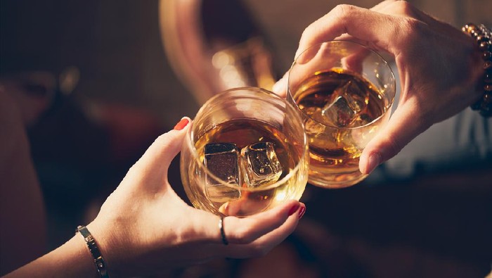 A couple makes a toast with two glasses of whiskey