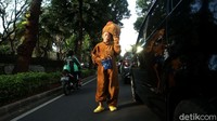 Dengan menggunakan kostum beruang ia berjalan mendekati kendaraan warga.