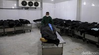 Seorang pekerja menyiapkan jenazah COVID-19 di kamar mayat pemakaman Behesht-e-Zahra, Teheran, Iran.