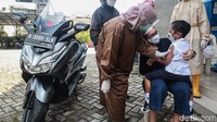 Seorang anak menangis di pangkuan orangtuanya saat akan diimunisasi.