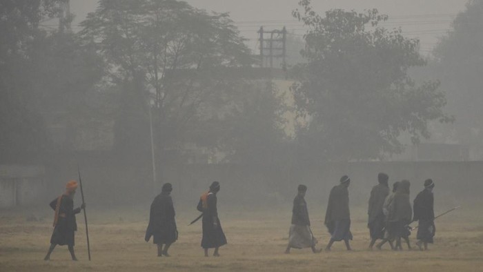 Sikh people walk along a field under heavy smog conditions after a Fateh Divas celebration a day after Diwali festival, in Amritsar on November 15, 2020. (Photo by NARINDER NANU / AFP)