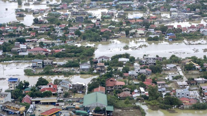 Potret Banjir Akibat Topan Vamco di Filipina In this photo provided by the Philippine Coast Guard, residents trapped on their roofs wave as a Philippine Coast Guard helicopter passes by for an aerial inspection at flooded areas in Cagayan valley region, northern Philippines Saturday, Nov. 14, 2020. Thick mud and debris coated many villages around the Philippine capital Friday after Typhoon Vamco caused extensive flooding that sent residents fleeing to their roofs and killing dozens of people. (Philippine Coast Guard via AP)